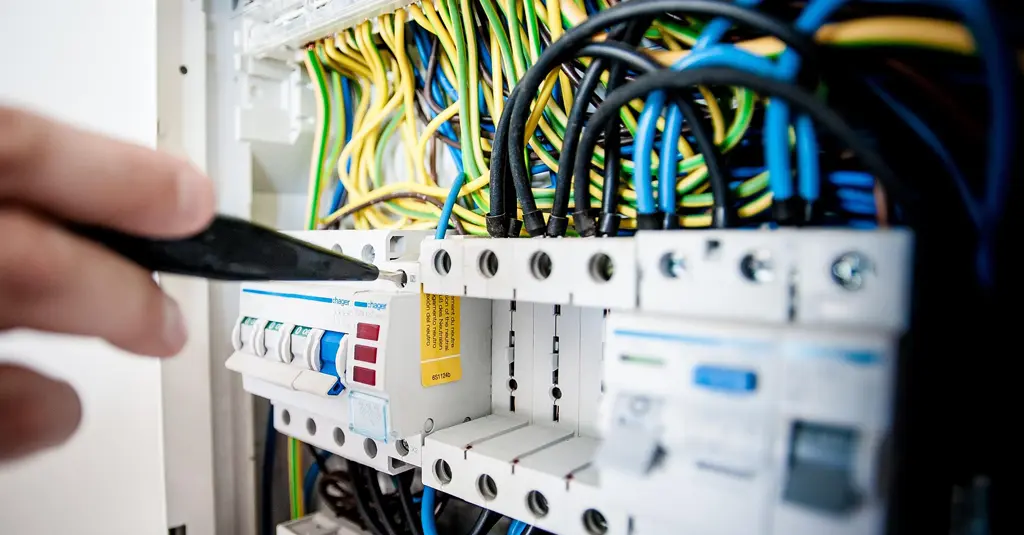 Électricien en micro-entreprise sur une installation, outil à la main